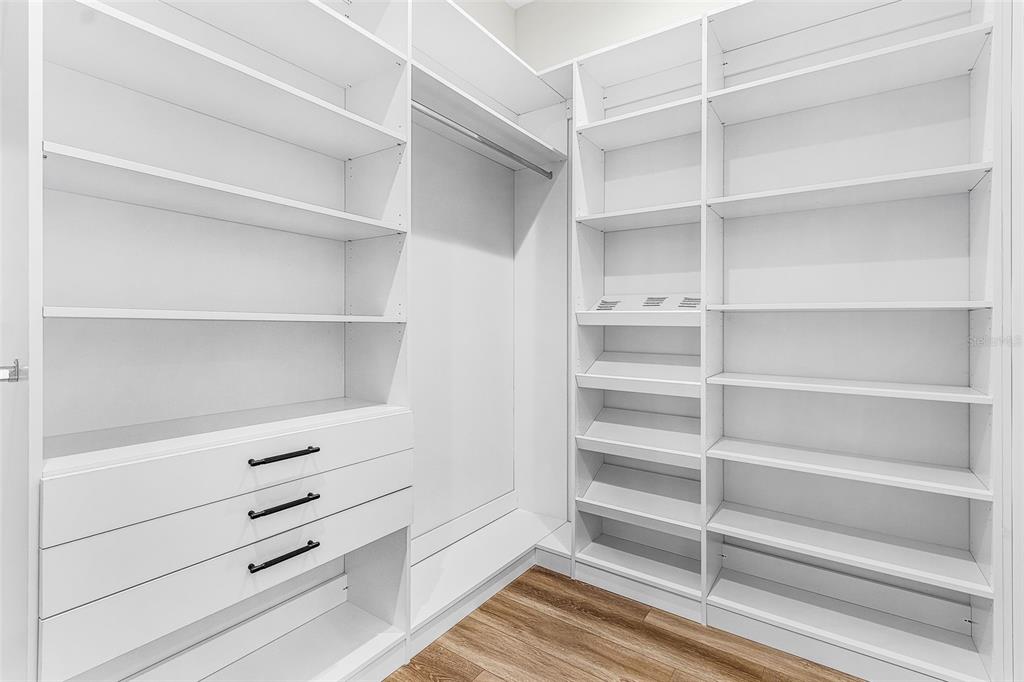 Atenia primary walk-in closet with white custom shelving and drawers