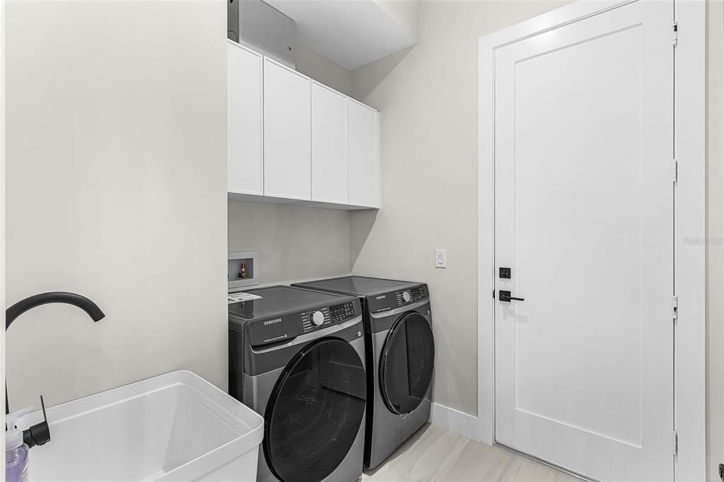 Atenia laundry room with washer, dryer, cabinetry and sink