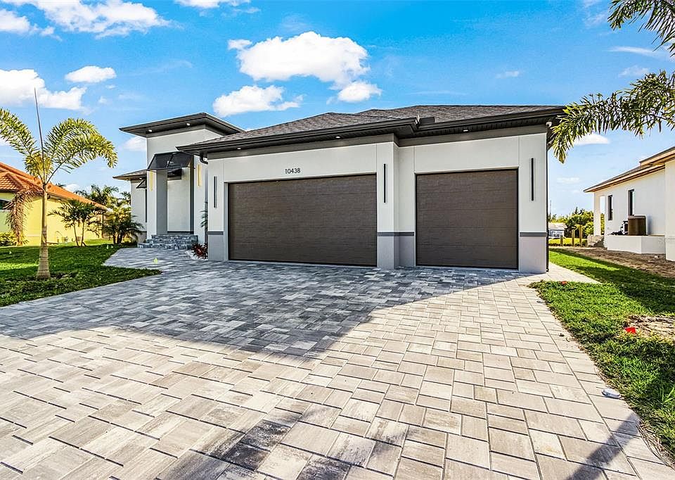 Atenia modern front exterior with paver driveway and three-car garage