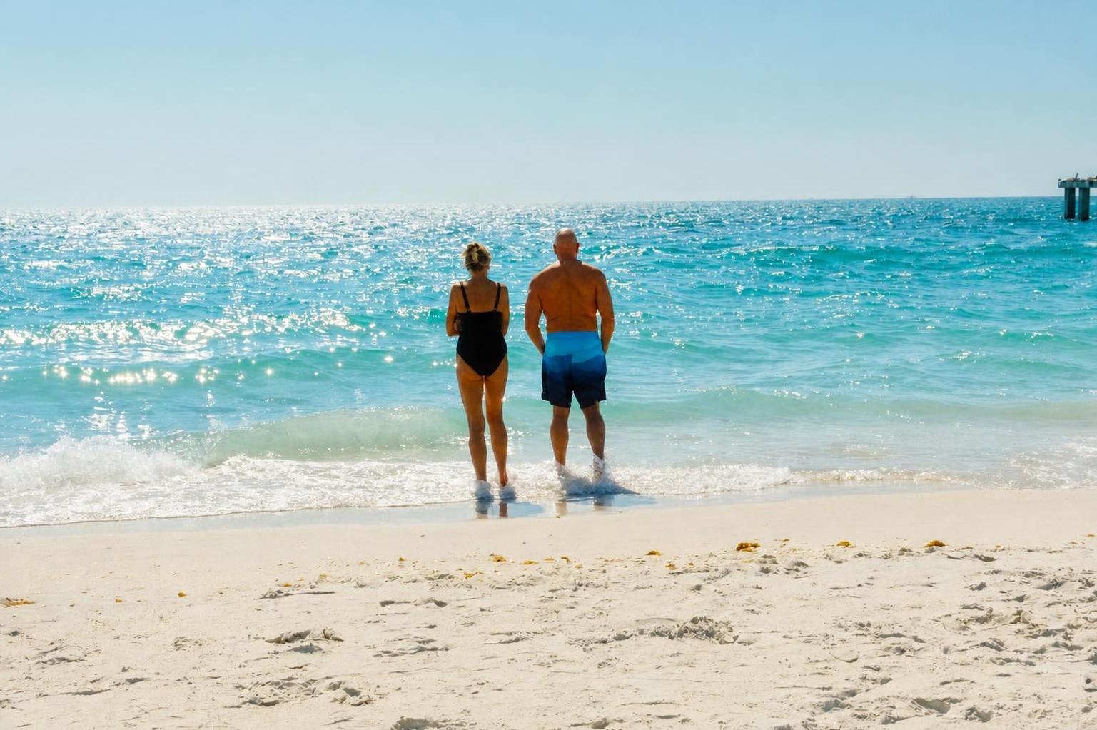 A couple standing together at the edge of ice-blue Gulf water on Boca Grande