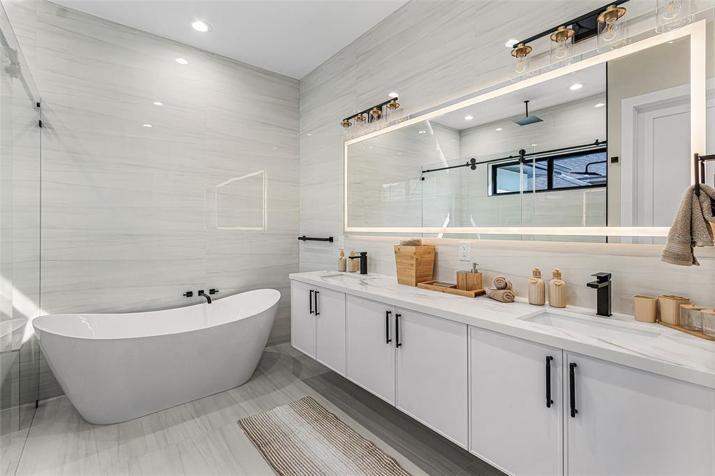Atenia primary bathroom with tub, shower, double vanity and wall tile