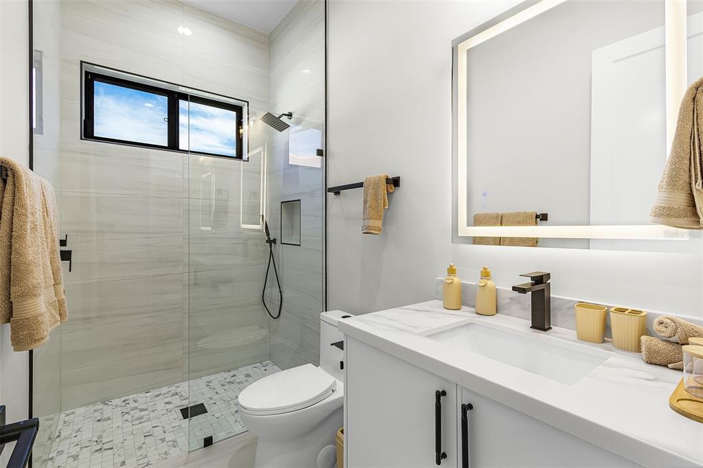 Atenia full bathroom with walk-in shower, vanity and window